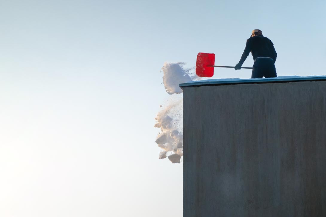 A person shovels snow on a roof