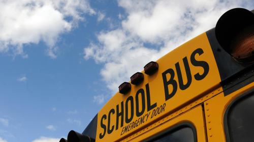 A yellow school bus and a blue cloudy sky